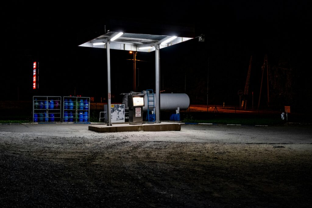 A solitary gas station illuminated at night, showcasing an industrial and moody atmosphere.